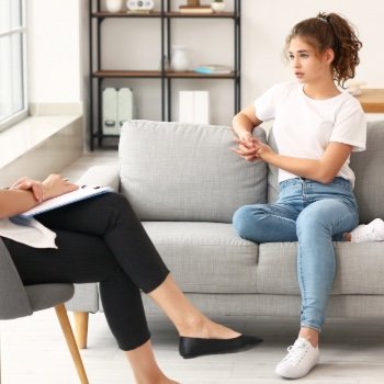 Young girl is seen sitting on the couch during her session with her therapist.